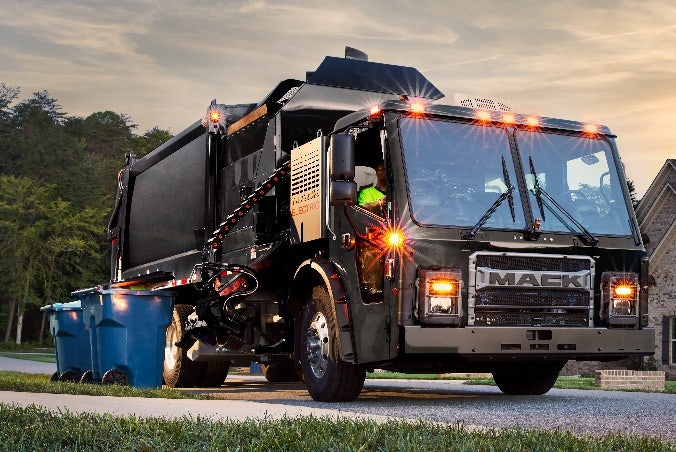 A garbage truck on the street Description automatically generated