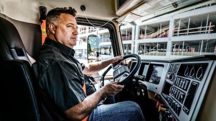 Driver operating a Mack truck equipped with a D-shaped steering wheel, showcasing a comfortable and ergonomic design
