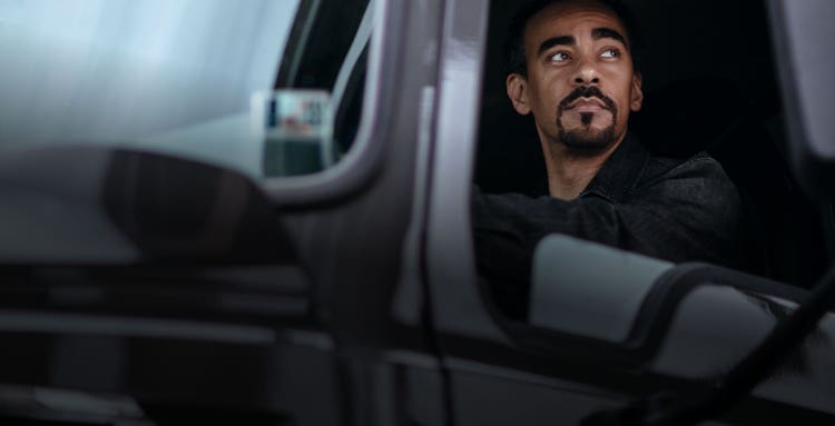 Closeup of a driver looking out of Mack truck cabin’s window.
