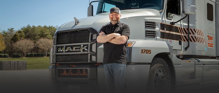 Closeup of a happy driver standing before the truck.