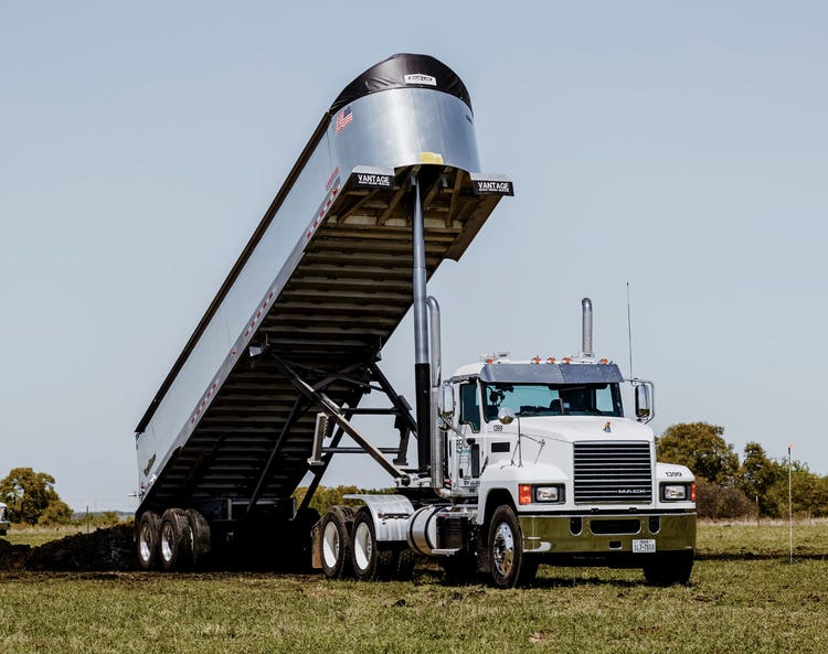 Mack Pinnacle dump truck unloading cargo.